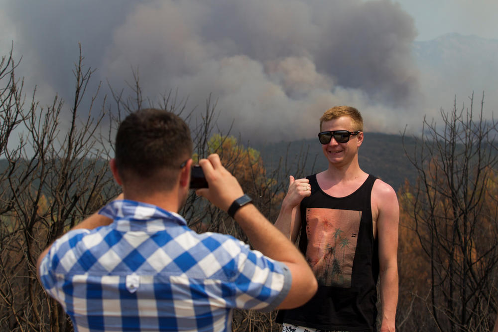 GORE NEBO I ZEMLJA, ON SE SJAJNO ZABAVLJA: Nasmejani turista pozira u Crnoj Gori s požarem u pozadini